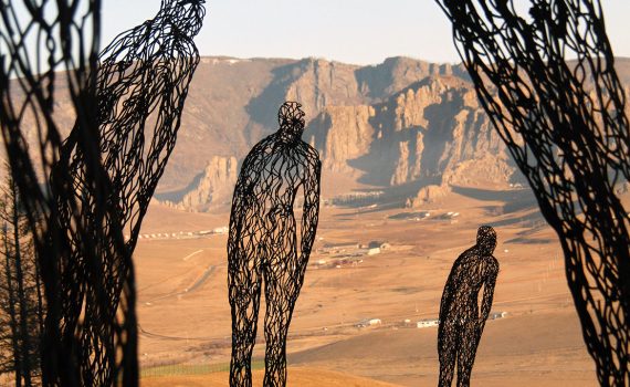 Photo of metal art figures in a dry, sunny landscape with blue sky